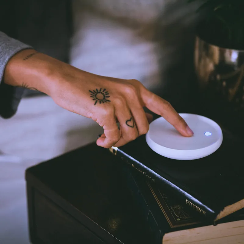 A hand reaching out in the dark to tap the top of the Dodow