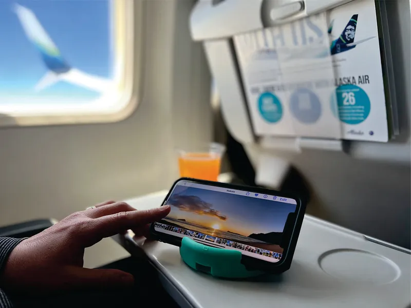 GoDonut na mesinha do avião, segurando o celular durante o voo