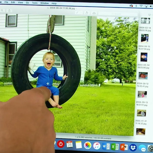 Ecrã de portátil com a foto de uma criança num baloiço de pneu e as miniaturas do ficheiro ao lado