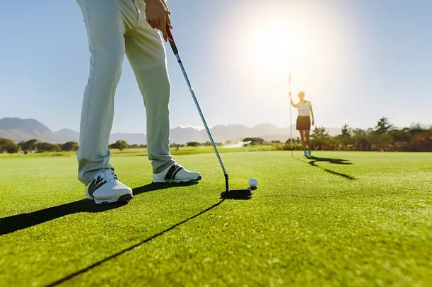 Jogador de golfe em pé no campo, no momento da tacada